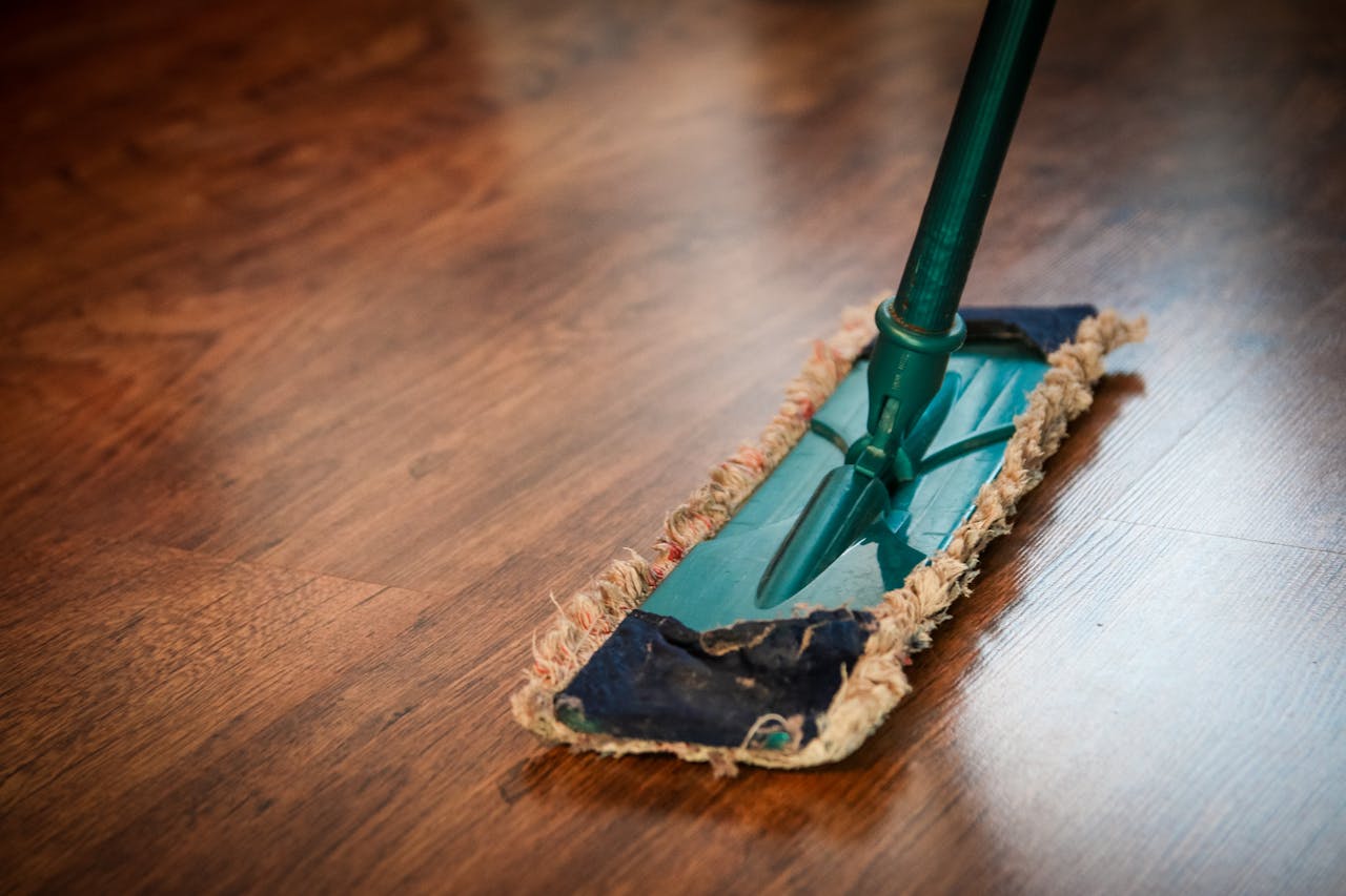 Dienstleistungen A detailed view of a mop cleaning a wooden floor, showing texture and pattern.